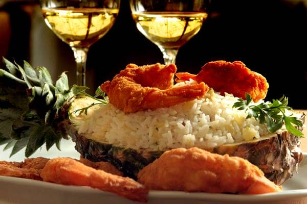 Camarão à dorê servido no abacaxi com arroz de passas e abacaxi salteado